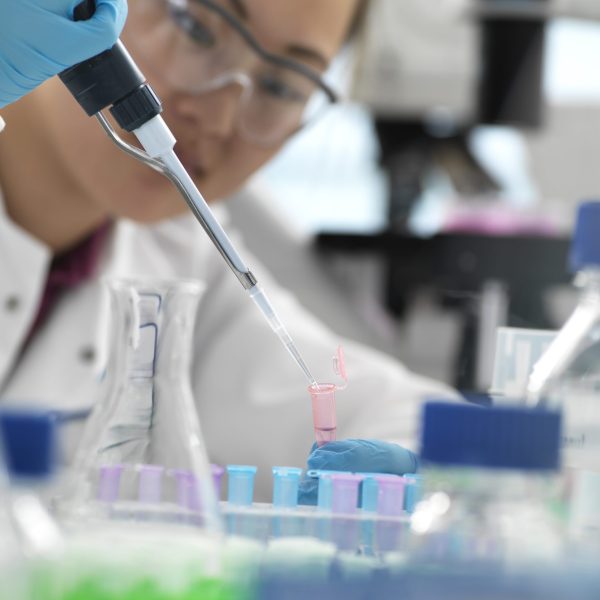 Scientist pipetting sample into vial during genetic experiment in laboratory