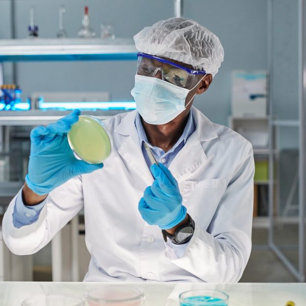 African young scientist in protective wear taking sample during scientific experiment in the laboratory, he examining new virus